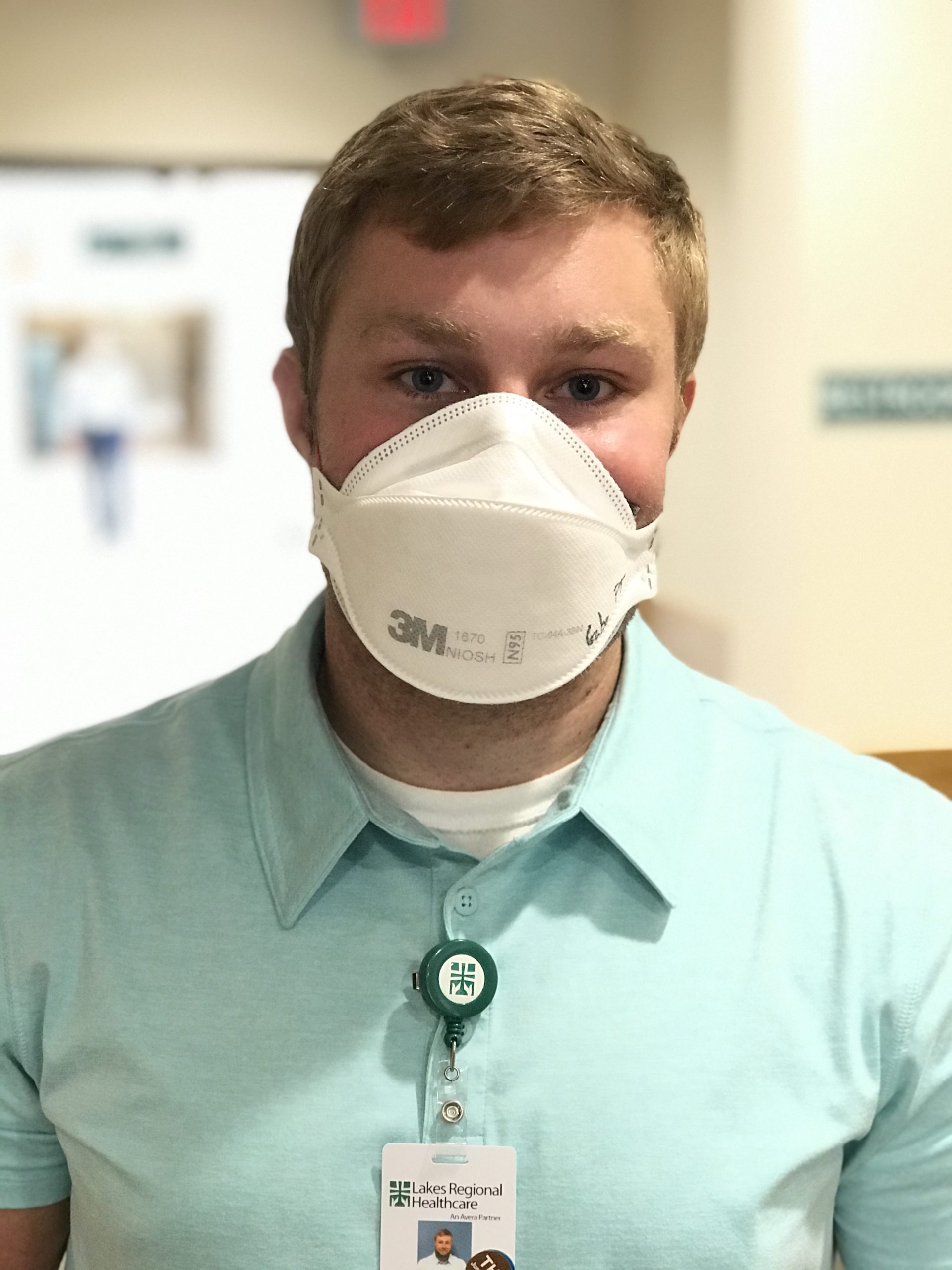 Gabe Goehring, DPT wearing a light green shirt, white face mask, and LRH name badge, looking at camera