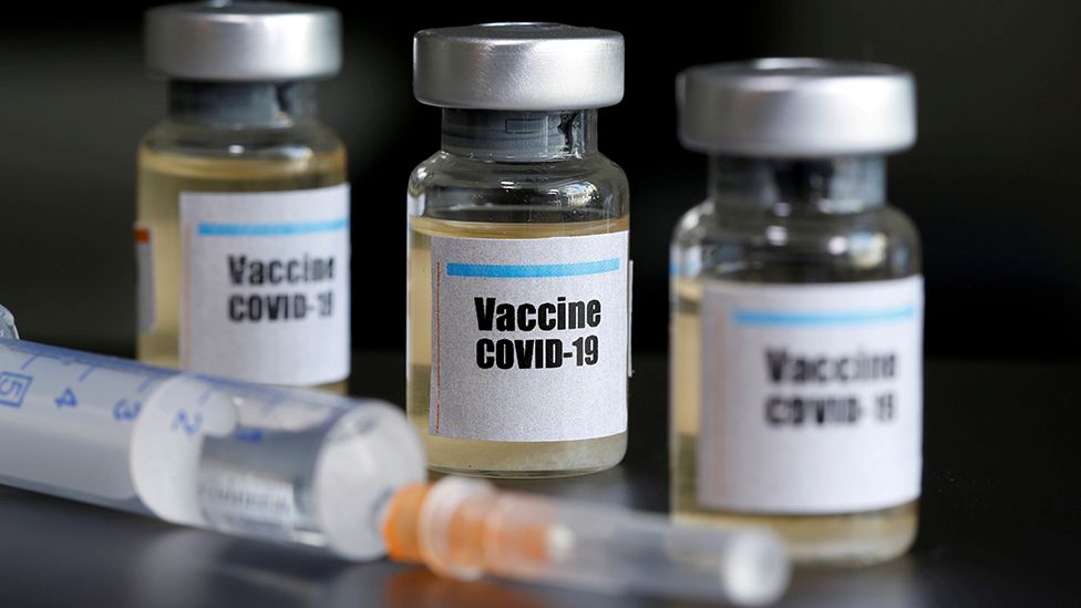 filled vials with note on outside that says "vaccine covid-19" and needle